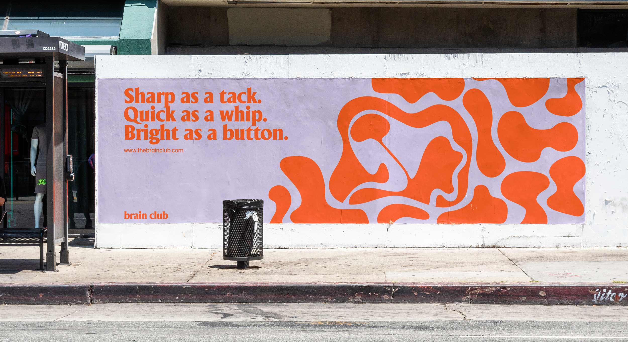 purple and orange pattern ad on a concrete wall beside a waiting shed